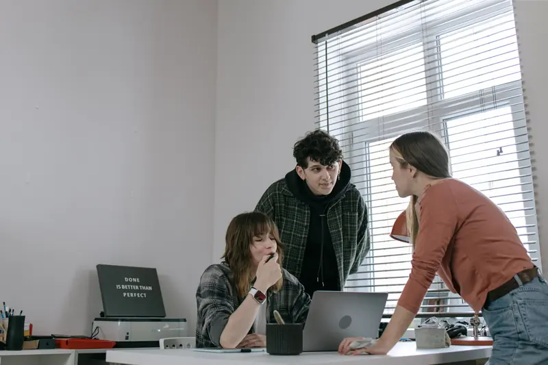 Software development team collaborating around a laptop